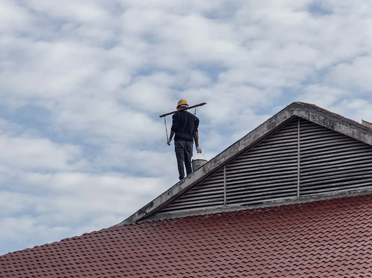 Roof Leak Repair in Monroe Township — a roofer walking along the ridge of a tile roof under an overcast sky