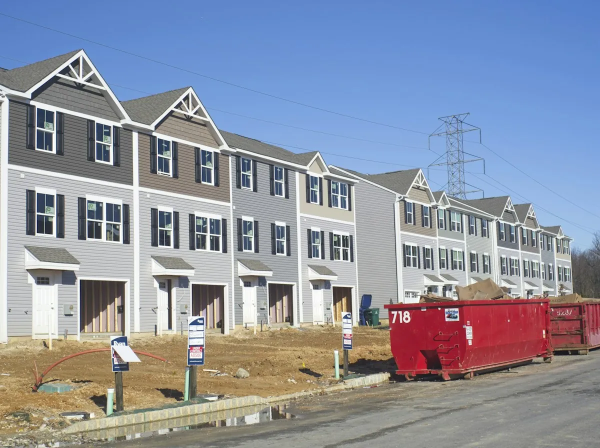 Roof Leak Repair in Monroe Township — a row of gray-sided townhouses with a roll-off dumpster at the curb